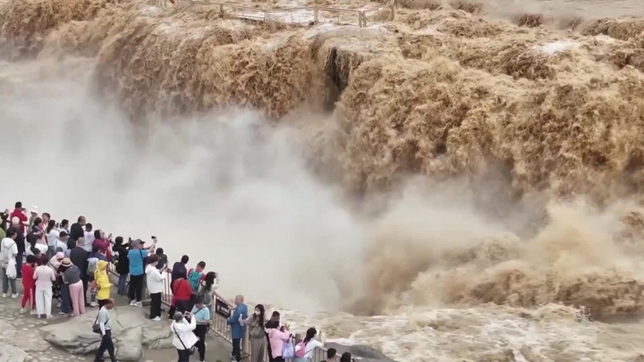 （视频截图）2026年5月25日，游客在山西省临汾市吉县黄河壶口瀑布旅游景区欣赏“金瀑飞流”壮美景观。日前，受黄河上游持续降雨影响，地处秦晋大峡谷的该景区水量骤增，瞬时流量超900立方米/秒，吸引众多游客慕名观赏。图片来源：CCTV+