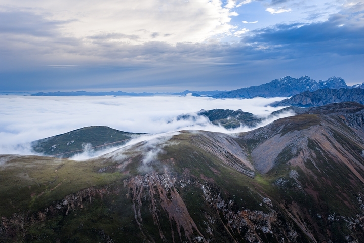 四川阿坝州，松潘县雪山梁观景台云海涌动。漫卷云雾萦绕连绵山峦，盘山公路穿梭云雾之间，远处雪峰隐现，壮阔高原云海风光尽显川西自然灵秀之美。